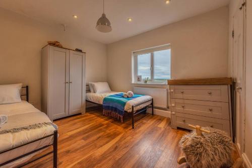a bedroom with two beds and a dresser and a window at Pass the Keys Charming Cottage Stunning Views in Cheswardine