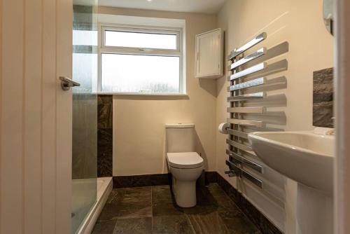 a bathroom with a toilet and a sink and a window at Pass the Keys Charming Cottage Stunning Views in Cheswardine