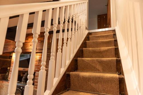 a staircase with white railings in a home at Pass the Keys Charming Cottage Stunning Views in Cheswardine