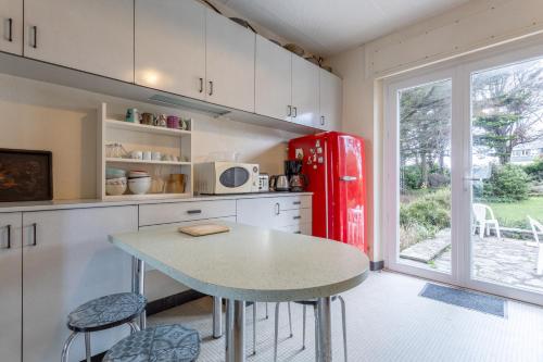 une cuisine avec une table et un réfrigérateur rouge dans l'établissement Maison trévignon à 100m de la plage, à Trégunc