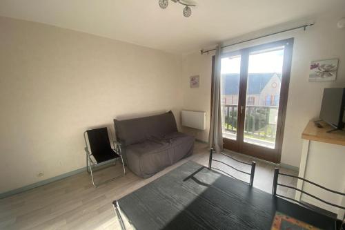 - un salon avec un canapé et une fenêtre dans l'établissement Bright T2 with balcony - close to the sea, à Ouistreham