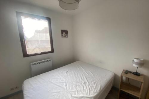 - une chambre avec un lit blanc et une fenêtre dans l'établissement Bright T2 with balcony - close to the sea, à Ouistreham