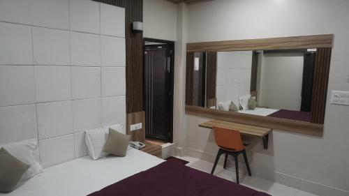 a bedroom with a bed and a desk and a mirror at Hotel Himalaya in Agartala