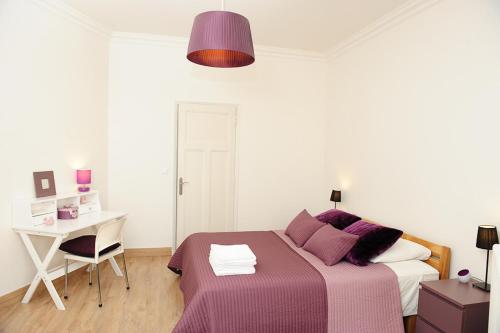 a bedroom with a bed and a desk with a purple blanket at Appartement Les Hortensias in Avignon