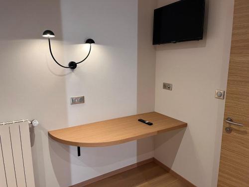 a room with a desk and a television on the wall at Logis Hotel Spa Restaurant Le Provence in Lanarce