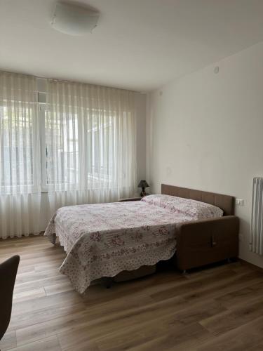 Monolocale Pordenone centro في بوردينوني: غرفة نوم بيضاء مع سرير مع لحاف من الزهور