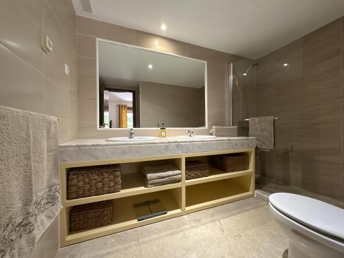 a bathroom with a sink and a mirror and a toilet at Spacious ground floor apartment in Punta Prima