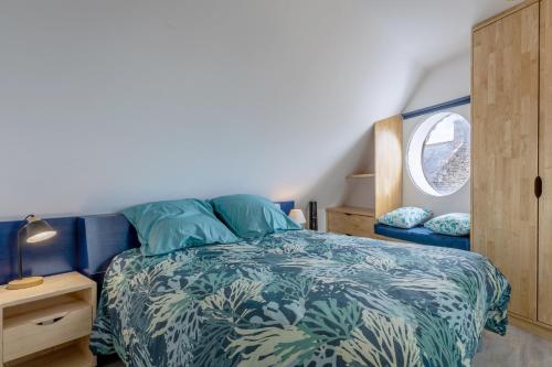 - une chambre avec un lit doté d'une couette bleue et d'une fenêtre dans l'établissement Penty house 500m de la plage, à Trégunc