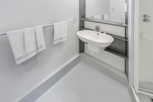 a white bathroom with a sink and towels at Modern Studios and Private Bedrooms with Shared Kitchen at Chapter Islington in London in London