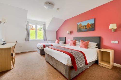 two beds in a room with red walls at Wookey Hole Hotel in Wells