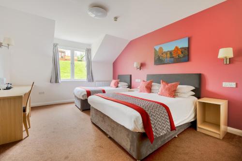 Wookey Hole Hotel في ويلْزْ: سريرين في غرفة بجدران حمراء