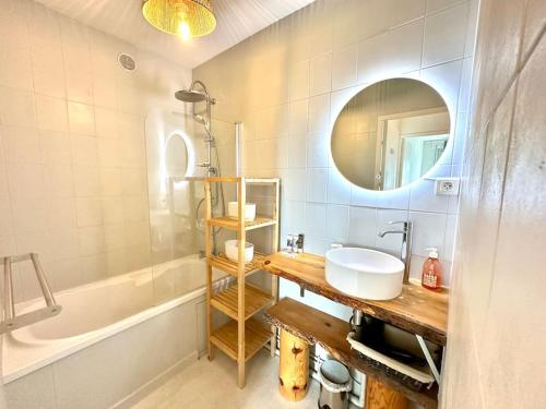 Un baño con lavabo, espejo y bañera. en Joli 2 pièces - Proche aéroport - Terrasse vue mer, en Niza