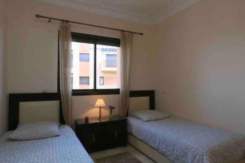 two beds in a bedroom with a window at Appart-Oasis Piscine et Terrasses in Marrakesh