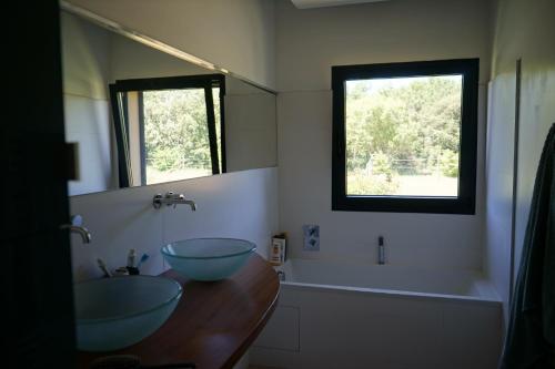 La salle de bains est pourvue de 2 lavabos, d'une baignoire et d'une fenêtre. dans l'établissement Belle Villa contemporaine au calme au milieu des chênes truffiers en drome provençale, à Visan