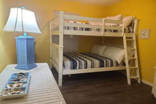 a bedroom with two bunk beds and a lamp at The Beach is Only Steps Away (F2) BEACHFRONT - Sleeps 8 in Gulf Shores