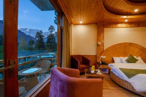 a bedroom with a bed and a balcony with a view at Tripli Hotels Namaste Manali in Manāli