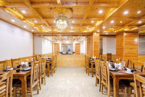 a dining room with wooden tables and chairs at Tripli Hotels Namaste Manali in Manāli