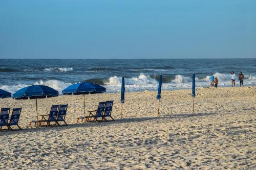 a group of chairs and umbrellas on a beach at The Beach is Only Steps Away (F2) BEACHFRONT - Sleeps 8 in Gulf Shores