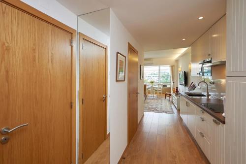 a kitchen with wooden cabinets and a hallway with a sink at Sea View 2 Mins Walk To Beach And Estoril Casino in Estoril