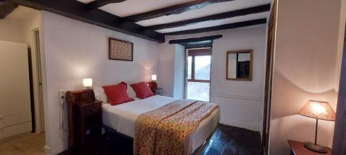 a bedroom with a bed with red pillows and a window at CASA RURAL Urruska in Elizondo