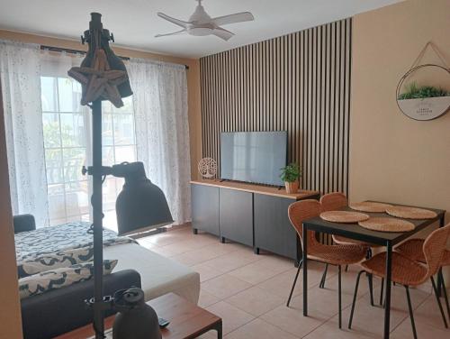 ein Wohnzimmer mit einem Bett, einem Tisch und einem TV in der Unterkunft Greatly located apartment with heated pool, Los Cristianos in Los Cristianos