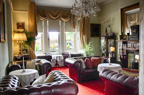 una sala de estar con sofás de cuero y una lámpara de araña. en Innisfree House en Dundalk