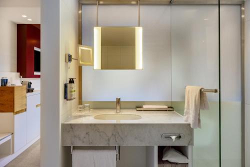a bathroom with a sink and a mirror at Pullman Eindhoven Cocagne in Eindhoven