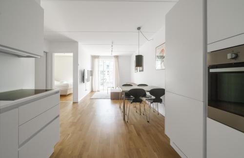 a kitchen and dining room with white cabinets and a table at Modern 2-bed apartment in Ørestaden in Copenhagen