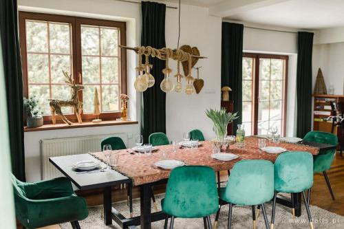 jadalnia ze stołem i zielonymi krzesłami w obiekcie Willa Radosna w Szczyrku