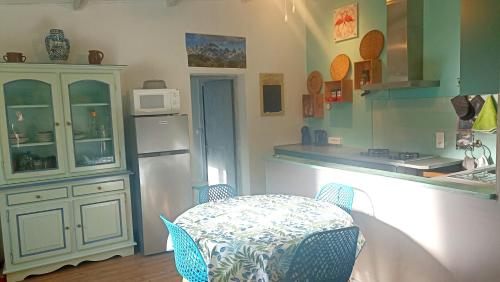 een keuken met een tafel, een koelkast en een aanrecht bij Charmant appartement au cœur de la montagne Corse in Zoza