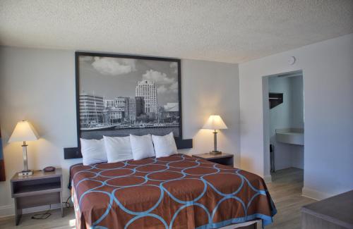 Cette chambre d'hôtel dispose d'un lit avec une grande photo sur le mur. dans l'établissement Super 8 by Wyndham Norfolk/Chesapeake Bay, à Norfolk