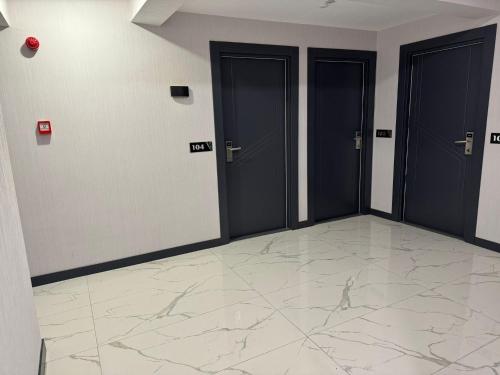 um corredor com três portas e um piso de mármore em Beyoğlu Palas Otel em Diarbaquir