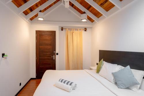 a bedroom with a white bed with a wooden ceiling at Brickwood Ganduvaru Private Villas in Rasdu