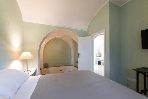 a bedroom with a white bed and an arched doorway at Masseria Borgo San Marco in Fasano