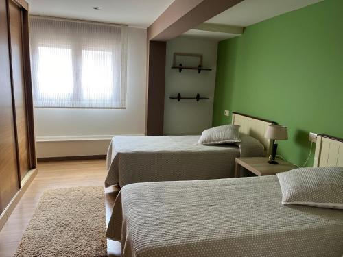 a green room with two beds and a window at Brisa mariña in Isla de Arosa