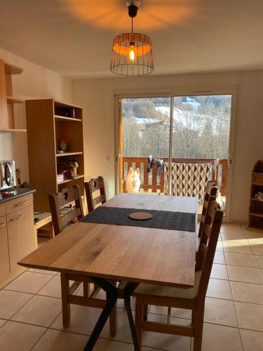 une cuisine avec une table en bois, des chaises et une fenêtre dans l'établissement Grand appartement Ancelle, à Ancelle