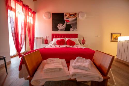 a bedroom with a bed with red sheets and a mask at Casa Rural El Capricho de Sandra in La Carrera