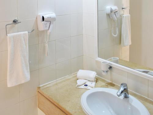 a bathroom with a sink and a mirror at Hotel Bougainvillier Djerba in Taguermess