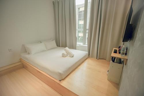 a small white bed in a room with a window at Double H Boutique Hotel in Kuala Terengganu