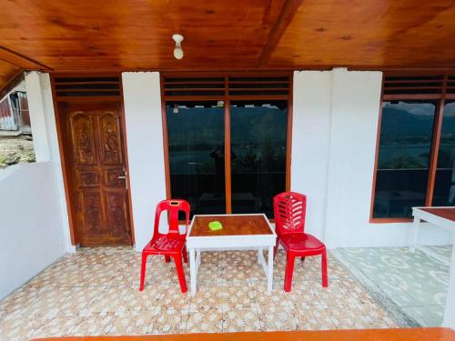 a patio with two red chairs and a table at Elsina guest house in Tuktuk Siadong