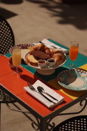 a table with a plate of pastries and glasses of orange juice at Hotel Terme Oriente - Beach & SPA in Ischia
