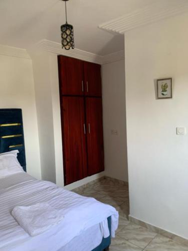 - une chambre avec un lit et une armoire en bois dans l'établissement Gokus Home, à Douala