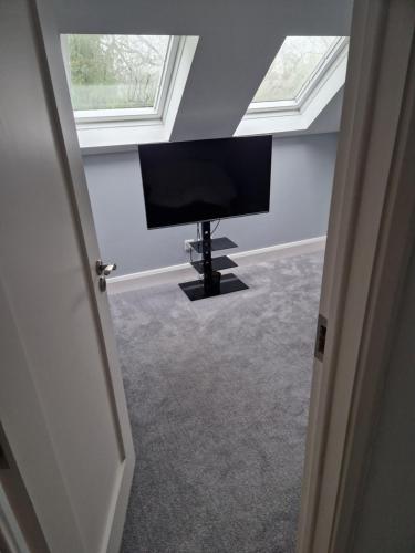 een flatscreen-tv in een kamer met 2 ramen bij Ashbury in Ballinasloe