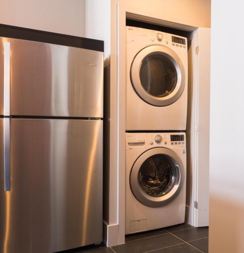 a stainless steel refrigerator and a washer and dryer at Les Lofts du Trésor - Par Les Lofts Vieux-Québec in Quebec City