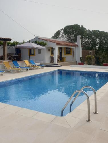 a swimming pool with chairs and a house at Sondela Self Catering in São Martinho do Porto