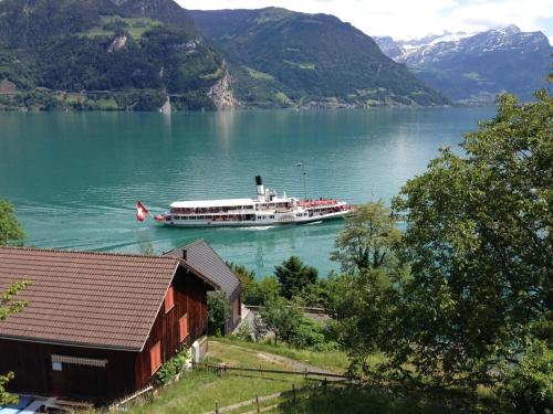 ein Boot auf einem See mit einem Haus und Bergen in der Unterkunft Rosenhof Bauen in Bauen