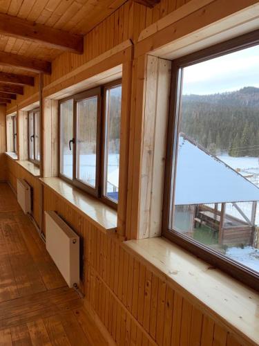 an empty room with windows in a wooden cabin at Під Явором in Vorokhta