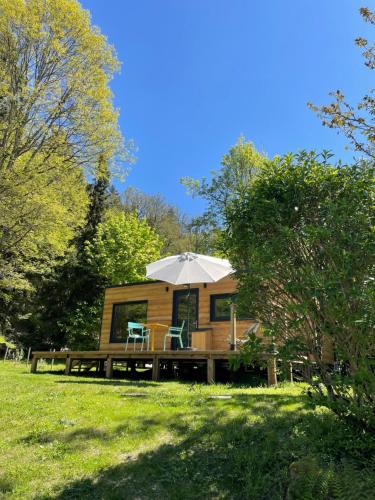 een hut met een parasol en een houten terras bij Moho Nat’ure Tiny-house in Saint-Nabord