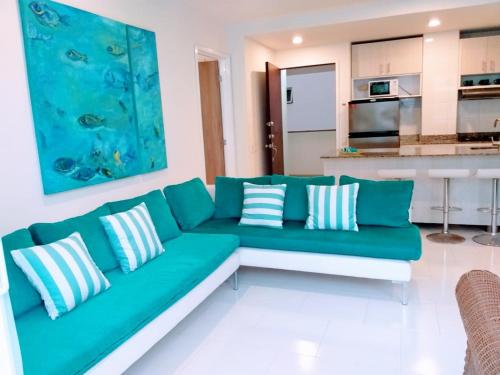 een woonkamer met een groene bank en een keuken bij Cartagena primera línea de playa azul vista al mar 2 in Cartagena