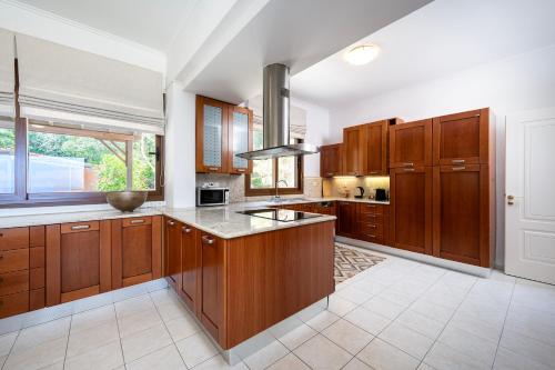 a large kitchen with wooden cabinets and a large window at Horizon Villa-Private Pool-7 Bedroom-Gym-Sea View in Psalidi